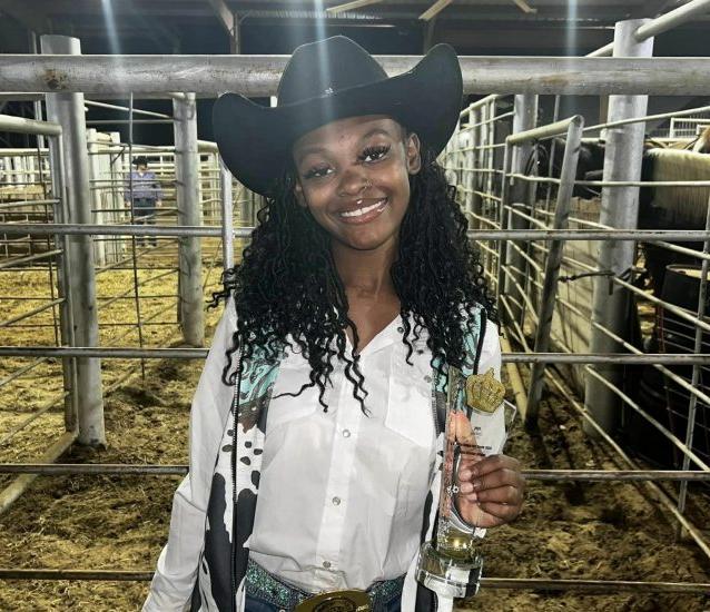 A person in western attire poses with a trophy.